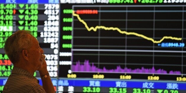 A man speaks in front of monitors showing market movements at the Taiwan Stock Exchange in Taipei on July 8, 2015. Taiwan's weighted index fell 274.05 points or 2.96 percent to 8,976.11 as a rout in China spread into regional markets while traders are also buffeted by fears about Greece's future in the eurozone. AFP PHOTO / Sam Yeh (Photo credit should read SAM YEH/AFP/Getty Images)