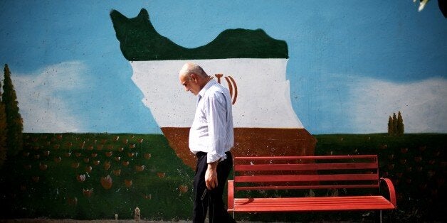 An Iranian man walks past a mural displaying the Iranian map adorned in the colours of the country's national flag, on June 2