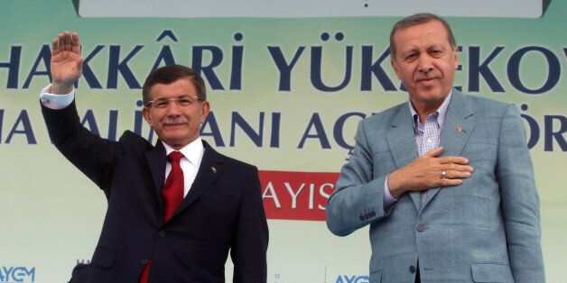 Turkey's President Recep Tayyip Erdogan, right, and Prime Minister Ahmet Davutoglu salute the people after Erdogan showed a copy of Islam's holy Quran, in Kurdish language during a ceremony in Hakkari, Turkey, Tuesday, May 26, 2015. Turkish opposition parties accuse Erdogan of exploiting religious values and symbols to favor the ruling Justice and Development Party ahead of the June 7 general elections. (AP Photo)