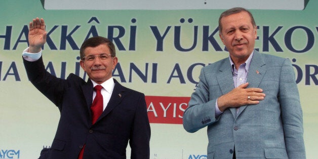 Turkey's President Recep Tayyip Erdogan, right, and Prime Minister Ahmet Davutoglu salute the people after Erdogan showed a c