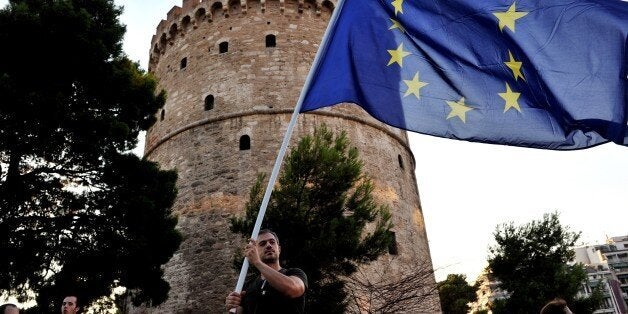 A pro-European Union protester holds an EU flag, during a demonstration outside the White Tower in Thessaloniki on July 9, 2015. Greece was to submit a detailed bailout request to its eurozone partners on July 9 in a last-ditch effort to save its collapsing economy and its place in the euro, in an unprecedented test of EU cohesion. With the crisis reaching a climax that could have unpredictable consequences, the EU president urged creditors to compromise on granting debt relief to Greece. AFP PHOTO / SAKIS MITROLIDIS-FRANCE OUT- (Photo credit should read SAKIS MITROLIDIS/AFP/Getty Images)