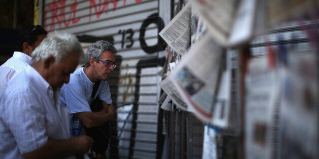 ATHENS, GREECE - JULY 10: Men read the newspapers outside a newsagent on July 10, 2015 in Athens, Greece. Greek prime minister Alexis Tsipras is presenting the new debt proposal to MP's today in parliament. The plan has aleady been given to Greece's creditors - the European Commission, the European Central Bank and the International Monetary Fund. (Photo by Christopher Furlong/Getty Images)