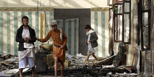 Armed Yemenis walk on the rubble of a wedding hall which was reportedly hit by a Saudi-led coalition air strike in the capita