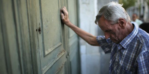 ATHENS, GREECE - JULY 07: A senior citizen leans against the door of a closed bank as he queues up to collect his pension outside a National Bank of Greece branch in Kotzia Square on July 7, 2015 in Athens, Greece. Greek Prime Minister Alexis Tsipras is working on new debt crisis proposals and is due to present them at a Eurozone emergency summit today. (Photo by Christopher Furlong/Getty Images)