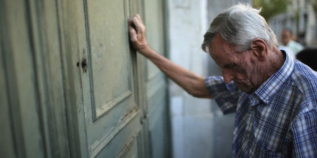 ATHENS, GREECE - JULY 07: A senior citizen leans against the door of a closed bank as he queues up to collect his pension ou