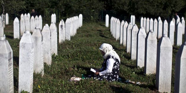 A woman prays amid tomb stones at the Potocari memorial complex near Srebrenica, 150 kilometers (94 miles) northeast of Sarajevo, Bosnia and Herzegovina, Saturday, July 11, 2015. Twenty years ago, on July 11, 1995, Serb troops overran the eastern Bosnian Muslim enclave of Srebrenica and executed some 8,000 Muslim men and boys, which International courts have labeled as an act of genocide, and newly identified victims of the genocide are still being re-interred at Srebrenica. (AP Photo/Marko Drobnjakovic)