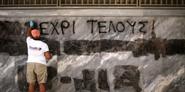 ATHENS, GREECE - JULY 14: A man cleans off the latest batch of anti-austerity graffiti from the walls of the Bank of Greece on July 14, 2015 in Athens, Greece. Greek Prime Minister Alexis Tsipras is meeting members of his party to discuss the eurozone bailout deal before a meeting in parliament to begin implementing bailout reforms. (Photo by Christopher Furlong/Getty Images)