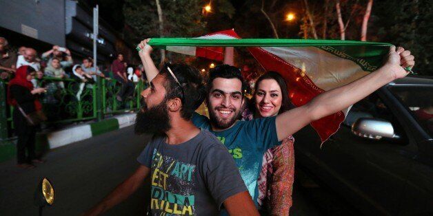 Iranian wave the national flag during celebration in northern Tehran on July 14, 2015, after Iran's nuclear negotiating team struck a deal with world powers in Vienna. Iranians poured onto the streets of Tehran after the Ramadan fast ended at sundown Tuesday to celebrate the historic nuclear deal agreed earlier with world powers in Vienna. AFP PHOTO/ATTA KENARE (Photo credit should read ATTA KENARE/AFP/Getty Images)