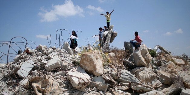 Palestinian children play in the rubble of houses destroyed during the 50-day war between Israel and Hamas militants in the summer of 2014, in the village of Khuzaa, east of Khan Yunis, in the southern Gaza Strip on July 7, 2015. AFP PHOTO / SAID KHATIB (Photo credit should read SAID KHATIB/AFP/Getty Images)