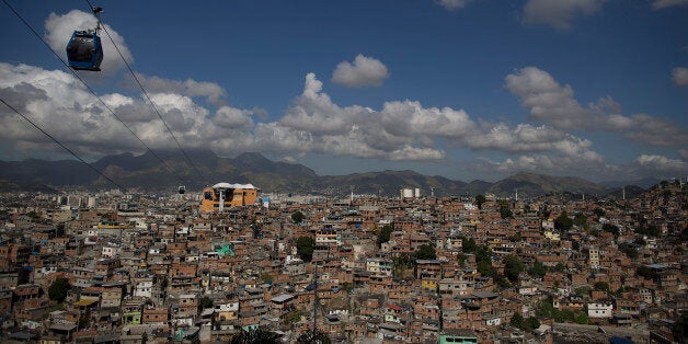 A cable car transports commuters over homes in the Complexo do Alemao shantytown in Rio de Janeiro, Brazil, Thursday, May 21, 2015 . The cable car system that spans the complex allows residents a faster commute and it has become a popular destination for foreign tourists on the weekend. (AP Photo/Leo Correa)