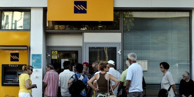 People wait to enter a bank, prior its opening on July 20, 2015 in Athens. Greek banks reopened on July 20 after a shutdown lasting three weeks imposed by the government to avert a crash in the banking system over the country's debt crisis. However, capital controls in force since June 29 remain in place, although a daily cash withdrawal limit of 60 euros ($65.03) has now been relaxed to a weekly restriction of 420 euros. AFP PHOTO / ARIS MESSINIS (Photo credit should read ARIS MESSINIS/AFP/Getty Images)