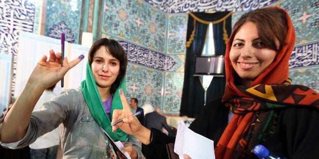 Iranian women display their ink-stained fingers as they cast their votes in the first round of the presidential election at a polling station in Tehran on June 14, 2013. Iranians are voting to choose a new president in an election the reformists hope their sole candidate will win in the face of divided conservative ranks, four years after the disputed re-election of Mahmoud Ahmadinejad. AFP PHOTO/ATTA ATTA KENARE (Photo credit should read ATTA KENARE/AFP/Getty Images)