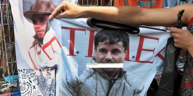 A vendor shows a t-shirt with the face of Joaquin 'El Chapo' Guzman Loera for sale in the popular and dangerous Tepito neighborhood in Mexico City on July 20, 2015. Nine days after Guzman escaped prison again, his legend has grown in his home region in northwestern Sinaloa state, where he is revered as a benevolent bandit despite his drug cartel's murderous record. Guzman escaped through a 1.5-kilometer (one-mile) long tunnel that was dug under the shower space of his prison cell in central Mexico, authorities said Sunday. AFP PHOTO / ALFREDO ESTRELLA (Photo credit should read ALFREDO ESTRELLA/AFP/Getty Images)