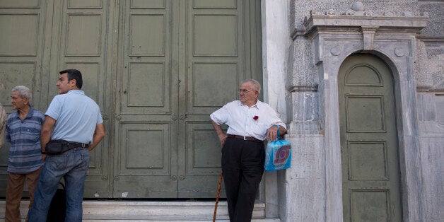 Pensioners stand outside the main gate of the national bank of Greece as they wait to withdraw a maximum of 120 euros ($134)