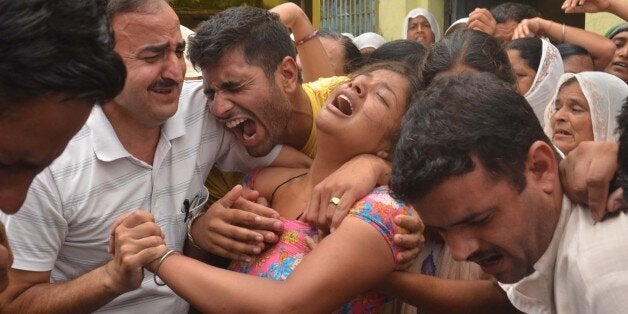 AMRITSAR, INDIA - JULY 28: Wailing family members of deceased Punjab police home guard jawan during cremation who was died in terrorist attack at Dina Nagar police station on July 28, 2015 in Amritsar, India. Heavily armed men dressed in military fatigues stormed a police station on Monday morning in Punjab's Gurdaspur district, killing four policemen, including Gurdaspur superintendent of police Baljit Singh, three civilians and three militants. Armed police exchanged fire with the attackers, who remained holed up in the police station 10 hours after the assault began at about 5 a.m. (IST). Preliminary probe indicates that the three suspected Lashker-e-Taiba militants had entered the country from Pakistan through Bamiyal village close to the International Border. They were carrying three AK 47 rifles, several Chinese-made grenades, besides 10 magazines with more than 200 rounds of ammunition. Global Positioning System (GPS) found on them showed that their final destination, the Dinanagar police station, was preset. (Photo by Sameer Sehgal/Hindustnan Times via Getty Images)