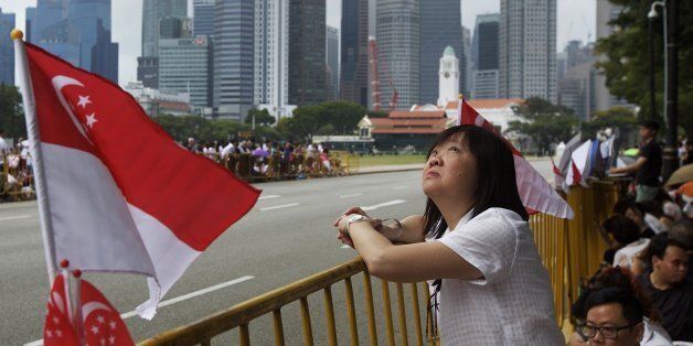 SINGAPORE - MARCH 29: A Singaporean woman looks up a the sky as she waits for the coffin carrying Lee Kuan Yew to pass by on March 29, 2015 in Singapore. Mr Lee Kuan Yew passed away on the morning of March 23, 2015 at Singapore General Hospital at the age of 91. Lee Kuan Yew was a Singaporean politician and the first Prime Minister of the country, governing for over 30 years and famed for his achievements in bringing a third world country to first world status in a single generation. (Photo by Ed Wray/Getty Images)