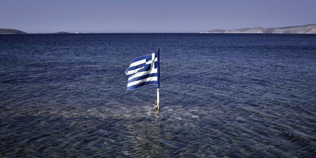 This photo taken on July 29, 2015 shows a Greek flag floating in the sea at the Kalamitsa beach on Skyros island. Greece expe