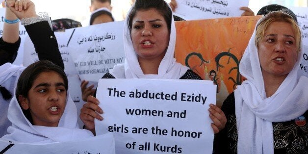 Iraqi Yazidi women hold placards during a protest outside the United Nations (UN) office in the Iraqi city of Arbil, the capi