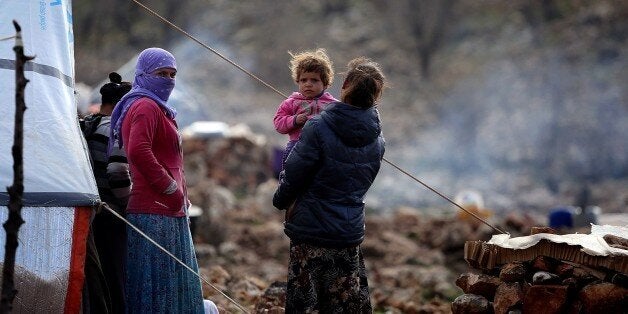 SINJAR, IRAQ - DECEMBER 20: Yezidis, fled from Islamic State of Iraq and Levant (ISIL) forces' attacks on their home town Sinjar, stay in harsh conditions as the winter starts, in a valley of western Sinjar Mountain in Sinjar district of Mosul, Irak on December 20, 2014. Yezidi women and a baby are seen out side of the tents. (Photo by Emrah Yorulmaz/Anadolu Agency/Getty Images)