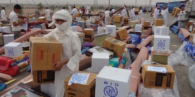 Iraqi men collect humanitarian aid supplies provided by the US development agency USAID to displaced Iraqis who have fled cla