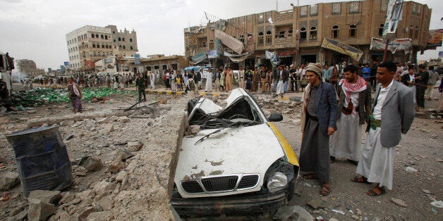 FILE - In this July 14, 2015, file photo, people stand next to a vehicle destroyed following airstrikes by the Saudi-led coalition in Sanaa, Yemen. In a report released Tuesday, Aug. 18, Amnesty International says all sides fighting in Yemen have left a âtrail of civilian death and destructionâ in the conflict, killing scores of innocent people in what could amount to war crimes. (AP Photo/Hani Mohammed, File)