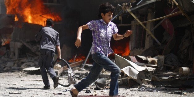 A Syrian youth runs past blood stains and debris following air strikes by government forces on the rebel-held town of Douma on August 20, 2015. Human Rights Watch urged the United Nations to impose an arms embargo on the Syrian government after air strikes on the Eastern Ghouta region town near the capital Damascus killed more than 100 people. AFP PHOTO / SAMEER AL-DOUMY (Photo credit should read SAMEER AL-DOUMY/AFP/Getty Images)