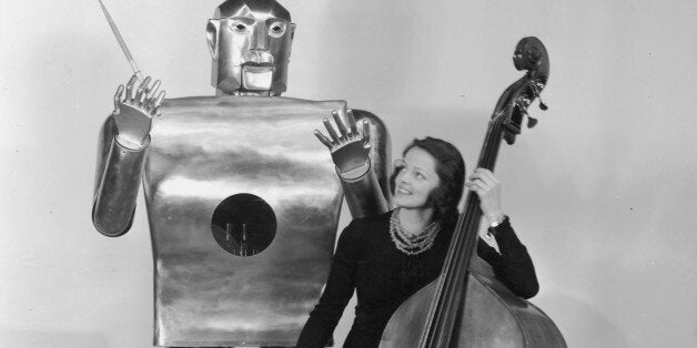 circa 1939: Musician Lois Kendall plays the cello while a mechanical man named Elektro 'conducts' on stage as part of a Westinghouse Electric and Manufacturing Co demonstration at the World's Fair, Flushing Meadow Park, Queens, New York City. (Photo by Hulton Archive/Getty Images)