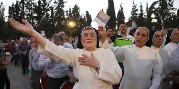 In this Saturday, Aug. 8, 2015 photo, Iraqi Christian refugees attend an outdoor prayer service to mark a year since their displacement, in Fuheis near Amman, Jordan. A year after tens of thousands of Iraqi Christians fled communities overtaken by Islamic State militants, their lives are on hold in exile: They won't go back to Iraq, saying it's not safe for Christians, but as refugees theyâre barred from working in temporary asylum countries such as Jordan. Expectations of quick resettlement to the West have been dashed. (AP Photo/Raad Adayleh)