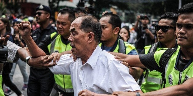 A protestor is detained by Malaysian police during a protest against Malaysia's Prime Minister Najib Razak in Kuala Lumpur on August 1, 2015. Najib on July 28 sacked his deputy premier and attorney general in a cabinet reshuffle widely seen as an attempt to strengthen his hold on power as he battles corruption allegations. AFP PHOTO / MOHD RASFAN (Photo credit should read MOHD RASFAN/AFP/Getty Images)