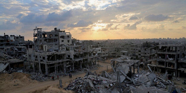 FILE - In this Oct. 12, 2014 file photo, Palestinians walk between the rubble of a destroyed building in Shijaiyah neighborhood of Gaza City in the northern Gaza Strip. A U.N. aid agency that helps Palestinians in Gaza says that after numerous delays, it's ready to begin helping a small number of people rebuild their homes, destroyed in last summer's war in the coastal strip. (AP Photo/Adel Hana, File)