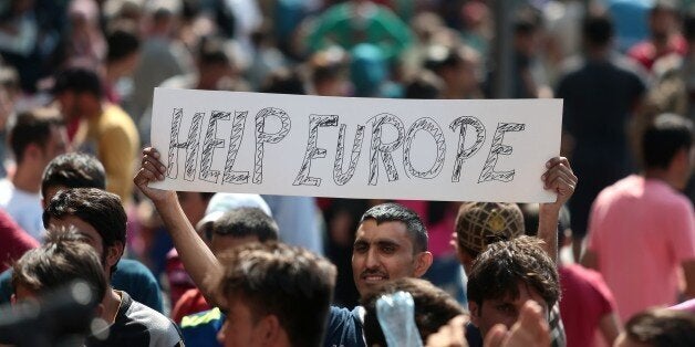 A man hold a placard reading 'Help Europe' as Syrian and Afgan refugees attend a protest rally to demand to travel to Germany on September 2, 2015 outside the Keleti (East) railway station in Budapest. Hungarian authorities face mounting anger from thousands of migrants who are unable to board trains to western European countries after the main Budapest station was closed. AFP PHOTO / FERENC ISZA (Photo credit should read FERENC ISZA/AFP/Getty Images)