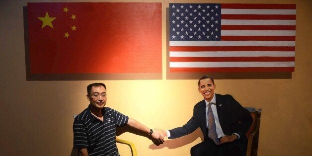 This photo taken on August 23, 2015 shows a visitor posing with a perspective painting of US President Barack Obama at the 4D Magic Fantasy exhibition during a beer festival in Qingdao, eastern China's Shandong province. CHINA OUT AFP PHOTO RESTRICTED TO EDITORIAL USE, MANDATORY MENTION OF THE ARTIST UPON PUBLICATION, TO ILLUSTRATE THE EVENT AS SPECIFIED IN THE CAPTION (Photo credit should read STR/AFP/Getty Images)