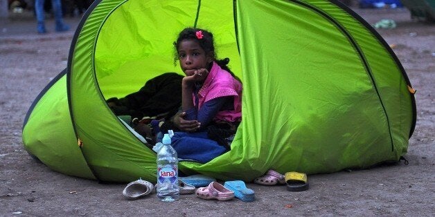 A young migrant sits in a tent in a park in Belgrade on September 9, 2015. The EU unveiled plans to take 160,000 refugees fro