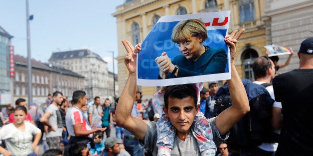 A man holds up a poster of German Chacellor Angela Merkel before starting a march out of Budapest, Hungary, Friday, Sept. 4, 2015. Over 150,000 people seeking to enter Europe have reached Hungary this year, most coming through the southern border with Serbia, and many apply for asylum but quickly try to leave for richer EU countries. (AP Photo/Frank Augstein)