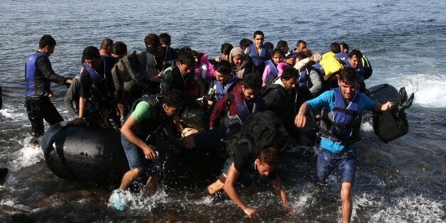 LESBOS ISLAND, GREECE - SEPTEMBER 09: Refugees on a rubber boat reach the shore of Eftalou beach, north of the port city of Mytilini after crossing the Aegean sea from Turkey on September 09, 2015 in Lesbos Island, Greece. (Photo by Ayhan Mehmet/Anadolu Agency/Getty Images)