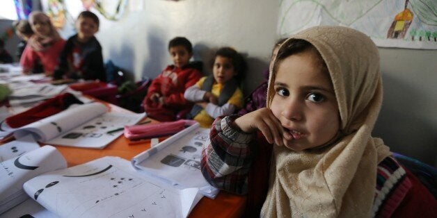 TO GO WITH AFP STORY BY RITA DAOUSyrian refugee children attend a class inside a tent at a Syrian refugees camp in the Lebanese village of Qaraoun, in the west of the Bekaa Valley on December 16, 2014. This school is one of the 47 education centres supervised by the International Rescue Committee (IRC) a non-governmental organisation in Lebanon, where some 1,1 million refugees have fled from the ongoing war in Syria. AFP PHOTO/JOSEPH EID (Photo credit should read JOSEPH EID/AFP/Getty Images)