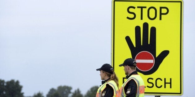 Police officers wait for passport control at a highway slip road at the German-Austrian border near the village of Passau, so