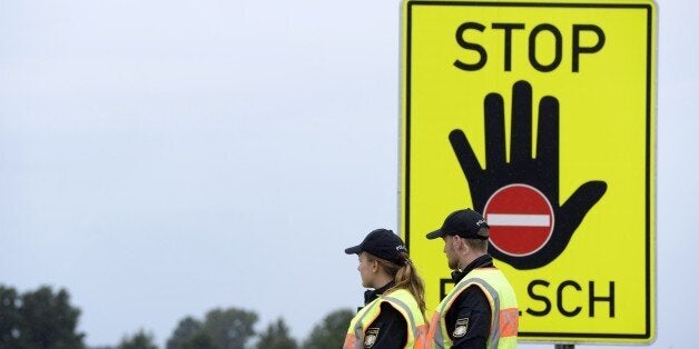 Police officers wait for passport control at a highway slip road at the German-Austrian border near the village of Passau, southern Germany, on September 14, 2015. Honking cars with stressed drivers banked up for kilometres (miles) at an Austrian-German road crossing Monday, hours after Berlin reimposed border checks in the face of a massive refugee influx. AFP PHOTO / CHRISTOF STACHE (Photo credit should read CHRISTOF STACHE/AFP/Getty Images)