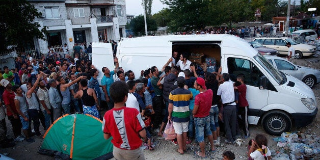 PRESHEVO, SERBIA - SEPTEMBER 04: Migrants from Iraq, Afghanistan and Syria press against each other while attempting to receive bread and water being distributed by a humanitarian group outside a Serbian processing facility September 4, 2015 in Preshevo, Serbia. After stopping at the Serbian processing facility, where the wait can last for three days, many of the migrants will continue north by bus to attempt to enter Hungary. Since the beginning of 2015 the number of migrants using the so-called 'Balkans route' has exploded with migrants arriving in Greece from Turkey and then travelling on through Macedonia and Serbia before entering the EU via Hungary. The number of people leaving their homes in war torn countries such as Syria, marks the largest migration of people since World War II. (Photo by Win McNamee/Getty Images)