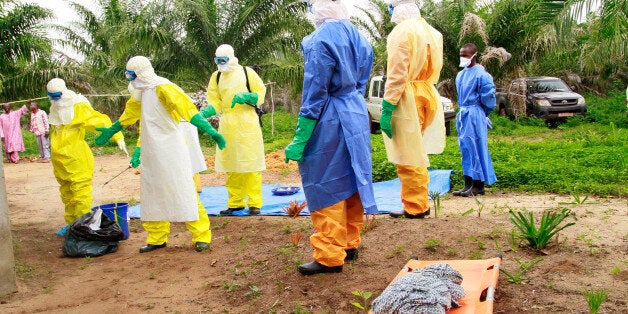 In this photo taken on Friday, June 19, 2015, the wrapped remains of a new born child suspected of contracting the Ebola virus, lays on a stretcher as health workers, dressed in Ebola protective gear, move the body for burial in Dubreka, Guinea. Despite hopes that the deadly Ebola outbreak could soon be contained in West Africa, it shows no signs of abating in Guinea and may be flaring up once more in Sierra Leone as people are flouting rules limiting travel meant to stop it. (AP Photo/Youssouf Bah)