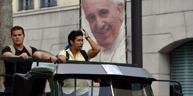 A welcome sign of Pope Francis marking his next visit to Cuba, is seen close to workers on a truck in Havana on September 17, 2015. The pope is visiting Cuba from September 19 to 22, the first stop on a trip that also will take him to the United States. In Cuba, he will visit Havana, the northeastern city of Holguin and Santiago de Cuba on the southeastern end of the island. AFP PHOTO / FILIPPO MONTEFORTE (Photo credit should read FILIPPO MONTEFORTE/AFP/Getty Images)