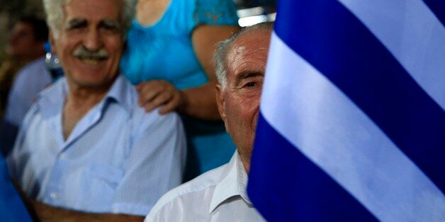 An elderly supporter of New Democracy party holds a Greek flag before the pre-election speech by party's leader Evangelos Meimarakis at Omonia square in Athens, Thursday, Sept. 17, 2015. Opinion polls indicate a race too close to call, with Syriza's leader and former Prime Minister Alexis Tsipras struggling to maintain the narrowest of leads over his main opponent, center-right New Democracy leader Evangelos Meimarakis. (AP Photo/Lefteris Pitarakis)