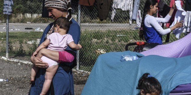 A refugee woman carries her baby at a makeshift refugee camp on the Serbian side of the border with Hungary near the town of
