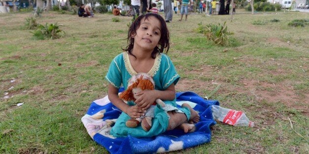A Syrian girl sits with a doll on September 17, 2015 at a park where around 1000 Syrians migrants are gathering in the Morocc