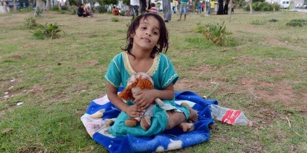 A Syrian girl sits with a doll on September 17, 2015 at a park where around 1000 Syrians migrants are gathering in the Moroccan town of Nador waiting to cross the border into the Spanish enclave of Melilla. Global aid charity Save the Children urged Madrid on Tuesday to help hundreds of Syrian refugee children reach Spanish territory in north Africa. AFP PHOTO /FADEL SENNA (Photo credit should read FADEL SENNA/AFP/Getty Images)