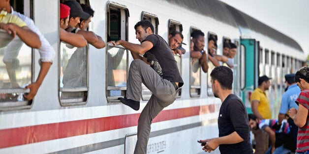 BELI MANASTIR, CROATIA - SEPTEMBER 18: Migrants climb through windows to board trains at the train station in Beli Manastir,