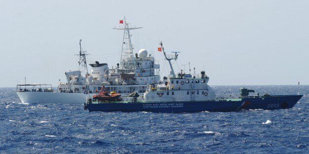 This picture taken on May 14, 2014 shows a Chinese coast guard ship (back) sailing next to a Vietnamese coast guard vessel (front) near China's oil drilling rig in disputed waters in the South China Sea. Vietnam is experiencing its worst anti-China unrest in decades following Beijing's deployment of an oil rig to disputed waters, with at least one Chinese worker killed and more than 100 injured. AFP PHOTO / HOANG DINH NAM (Photo credit should read HOANG DINH NAM/AFP/Getty Images)