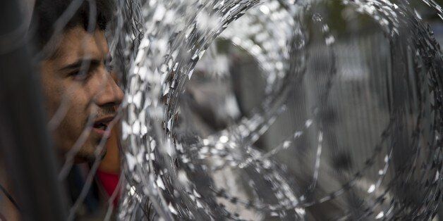 HORGOS, SERBIA - SEPTEMBER 16 : A refugee looks through the razor-wire fence at the Horgos border, near the town of Kanjiza after Hungarian authorities closed their border in Horgos, Serbia on September 16, 2015. (Photo by Arpad Kurucz/Anadolu Agency/Getty Images)
