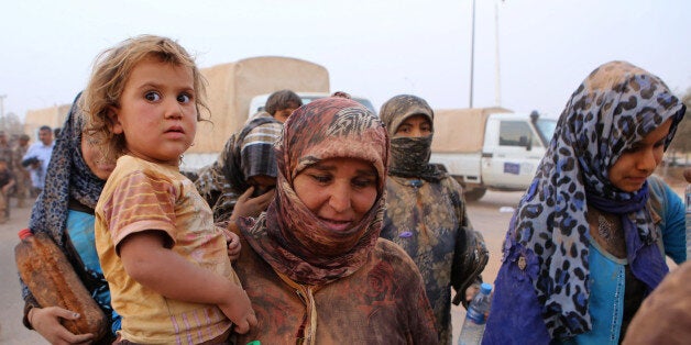 In this Thursday, Sept. 10, 2015 photo, Syrian refugees are covered in dust on arrival at the Trabeel border after crossing i