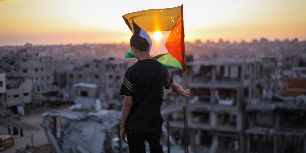 GAZA, PALESTINE - 2014/09/19: A Palestinian child raises the flag of Palestine over the rubble of his ruined home, because of the Israeli war on Gaza. (Photo by Ibrahim Khader/Pacific Press/LightRocket via Getty Images)